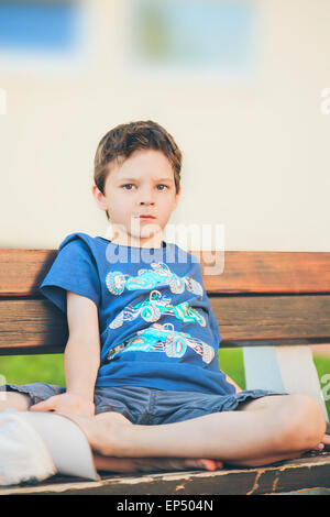 traurige Junge sitzt auf einer Bank Stockfoto