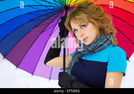 Junge Frau mit mehrfarbigen Regenschirm im Winterwald Stockfoto