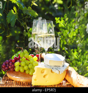 Verschiedene Arten von Käse, Brot, Trauben und zwei Gläser Weißwein Stockfoto