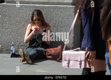 iPhone Handy-Benutzer Benutzer Sonnenschein betrachten ihre Telefone außerhalb der Apple-Store in Covent Garden Stockfoto