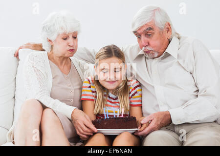 Kleine Mädchen und Großeltern die Kerzen ausblasen Stockfoto