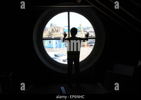 10 Jahre alten englischen junge Blick aus dem Fenster der Leuchtturm in Trinity Buoy Wharf Leuchtturm. Stockfoto