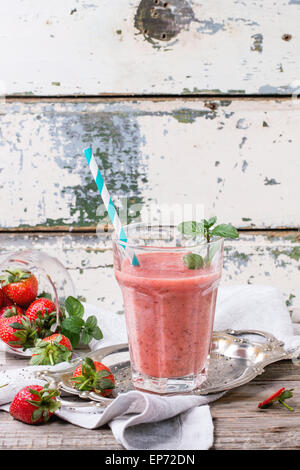 Glas rote Erdbeere Smoothie mit Chia-Samen, serviert mit retro cocktail Rohr, frischer Minze und Erdbeeren über Holztisch Stockfoto