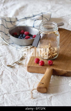 In das Glasgefäß mit hausgemachtem Müsli verzieren Typenschild serviert mit Himbeeren und Brombeeren auf Holzbrett über Stockfoto