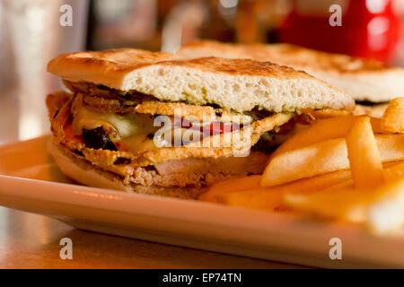 Gegrillte Hähnchen und Portobello Pilze Panini mit knusprigen Zwiebelringen und einer Seitenlänge von goldene Pommes frites Stockfoto