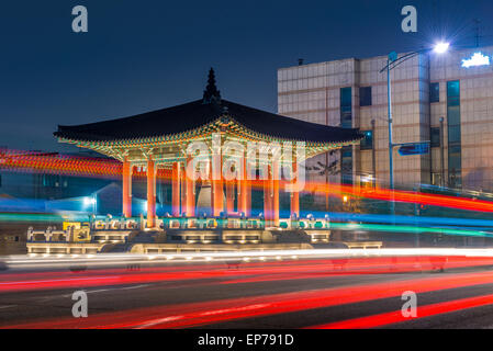 Nachtverkehr verwischt vorbei an der Glocke Pavillon in Hwaseong-Festung in Suwon, Südkorea. Stockfoto