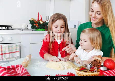 Zwei entzückenden Mädchen mit ihrer Mutter Weihnachtsplätzchen Backen Stockfoto