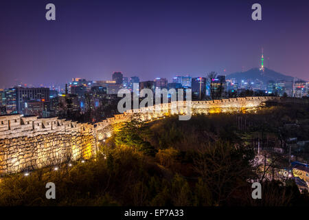 Die alte Stadtmauer beleuchtet abends wie die Lichter der Innenstadt von Seoul Glanz in der Ferne. Stockfoto