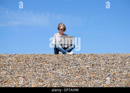 ältere Frau mit Laptop-Computer am Strand Stockfoto