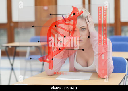 Blonde Frau denken schwer während des Studiums auf futuristische Schnittstelle mit DNA Stockfoto
