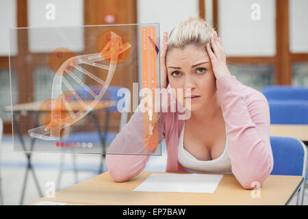 Blonde Frau denken schwer während des Studiums auf Schnittstelle mit DNA Stockfoto