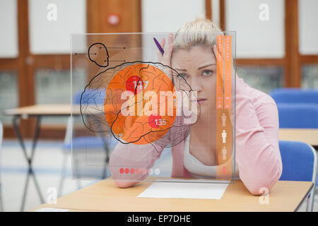 Blonde Frau denken schwer während des Studiums auf Schnittstelle mit Gehirn Stockfoto
