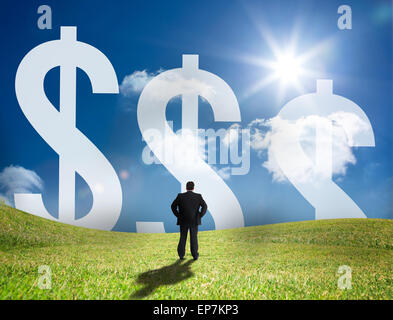 Geschäftsmann sucht bei großen Dollarzeichen am Horizont Stockfoto