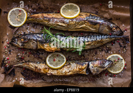 Ganzer Fisch mit Gewürzen, Zitrone und Rosmarin in einen Bräter Pfanne mit Backpapier gebacken Stockfoto