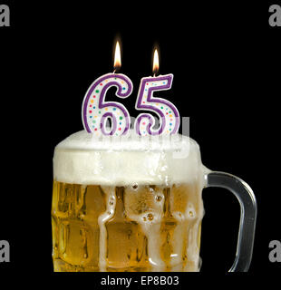 Beleuchteten Geburtstagskerzen im Krug Bier zum 65. Geburtstag, isoliert auf schwarz. Stockfoto