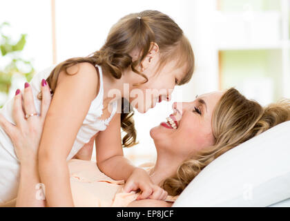 Glückliche Mama spielt mit ihrem Kind im Bett genießen sonnige Morgen im Hause Schlafzimmer Stockfoto