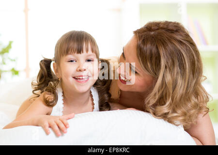 Porträt von einer freudigen Mutter und Tochter Kind auf Bett liegend Stockfoto