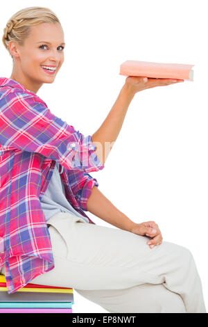 Schöne Frau zeigt ein Buch und lächelt in die Kamera Stockfoto