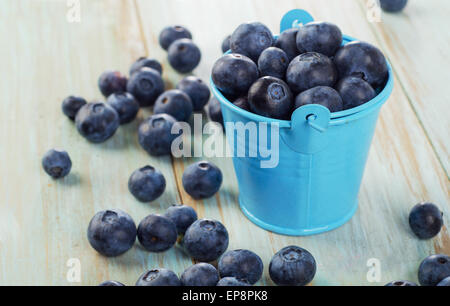 Heidelbeeren in kleinen Eimer auf Holztisch. Stockfoto