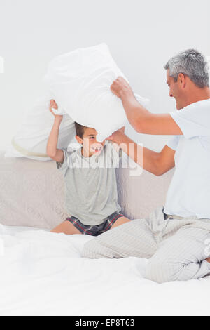 Vater und Sohn kämpfen zusammen mit Kissen auf Bett Stockfoto