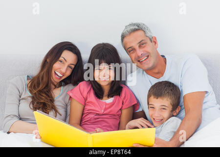 Lächelnd Familie betrachten gemeinsam ihr Fotoalbum im Bett Stockfoto