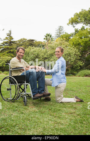 Attraktiver Mann im Rollstuhl mit Partner kniet neben ihm Stockfoto