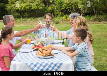 Multi-Generationen-Familie Toasten einander beim Abendessen außerhalb Stockfoto