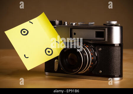 Post-It note mit Smiley-Gesicht geklebt auf einer Fotokamera Stockfoto