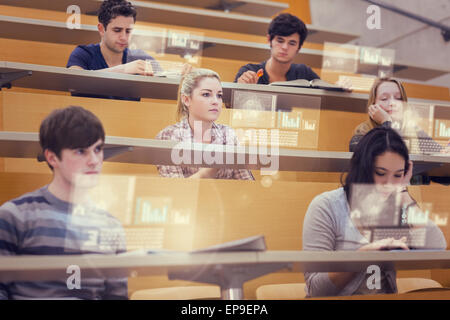 Studenten im Hörsaal auf ihre futuristischen Tablet arbeiten konzentriert Stockfoto