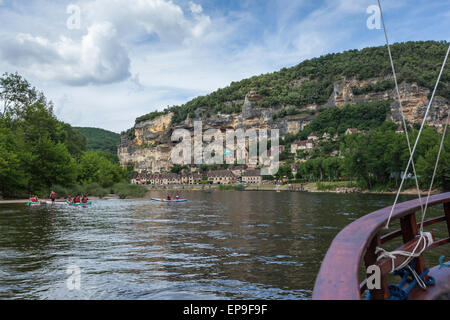 Kanufahren auf dem Fluss Dordogne in La Roque-Gageac, Dordogne, Frankreich mit den felsigen Klippen und Dorf im Hintergrund vor einem blauen Himmel mit Wolken Stockfoto