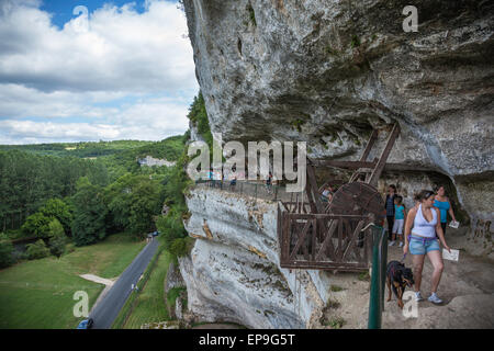 Touristen sehen die Artefakte in La Roque Saint Christophe, Dordogne, Frankreich mit einem Blick auf die Klippe über das bewaldete Tal an einem hellen Tag im Sommer Stockfoto