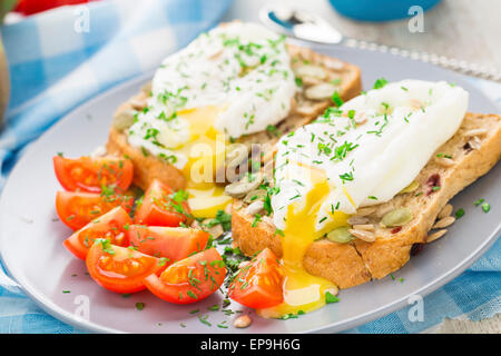 Frühstücks-Sandwich mit pochiertem Ei und Cherry-Tomaten. Stockfoto