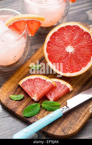 Grapefruit mit Scheiben auf einem Holztisch. Stockfoto