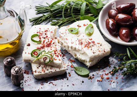 Feta-Käse mit Oliven und grünen Kräutern auf grauem Marmor Hintergrund Stockfoto