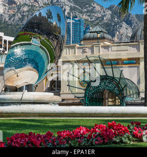 Ein Spiegelbild des Kasinos in einem Metall-Skulptur und Cafe de Paris Eingang im Hintergrund in Monte Carlo, Monaco Stockfoto