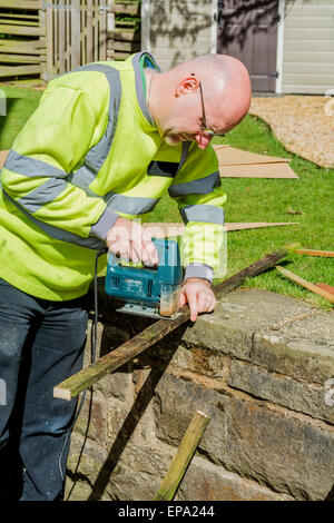 Dieser Mann ist Schnittlängen von Holz mit einer Stichsäge Hand gehalten. Stockfoto