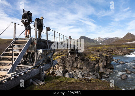 Wanderer, die über eine Brücke über den Fluss Kaldaklofskvisl auf dem Laugavegur-Wanderweg, Island Stockfoto
