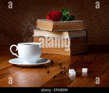 Heiße Tasse frischen Kaffee auf den Holztisch und Stapel Bücher mit roter Rose lesen Stockfoto