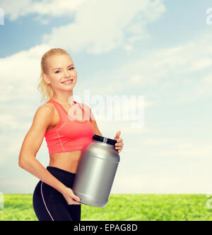 lächelnde sportliche Frau mit Glas des Proteins Stockfoto