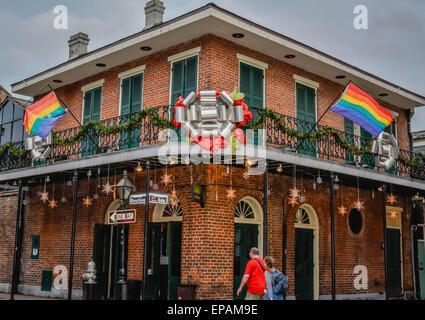 Regenbogenfahnen fliegen hoch über Ecke Geschäft mit Balkon und Urlaub Dekorationen auf St. Ann und Bourbon Street im French Qua Stockfoto