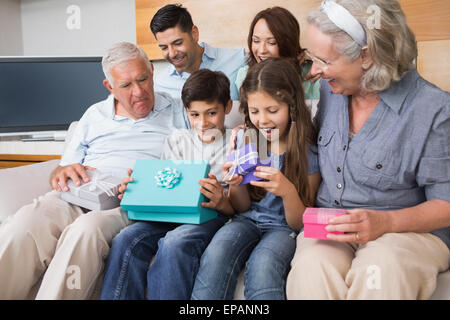Großfamilie auf Sofa mit Geschenk-Boxen im Wohnzimmer sitzen Stockfoto