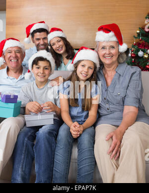 Großfamilie in Weihnachtsmützen mit Geschenk-Boxen im Wohnzimmer Stockfoto