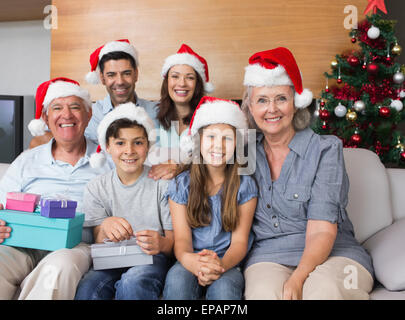 Großfamilie in Weihnachtsmützen mit Geschenk-Boxen im Wohnzimmer Stockfoto