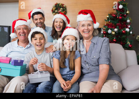 Großfamilie in Weihnachtsmützen mit Geschenk-Boxen im Wohnzimmer Stockfoto