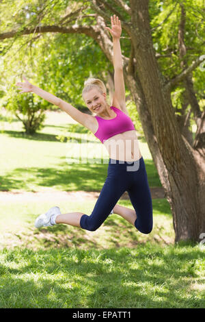 Gesamte Länge der Frau im springen im Park Sportbekleidung Stockfoto