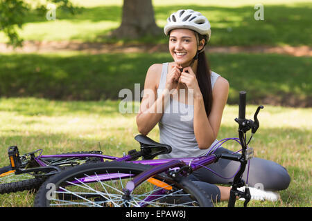 Stets gut gelaunte Frau Helm neben Fahrrad im park Stockfoto