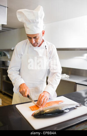 Konzentriert männlichen Chef schneiden Fisch in Küche Stockfoto