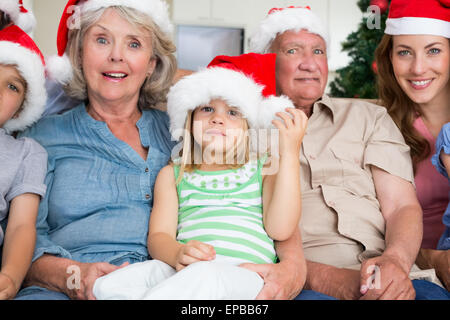 Fortpflanzungsfähigkeit Familienglück Santa Hüte zu tragen, auf der couch Stockfoto