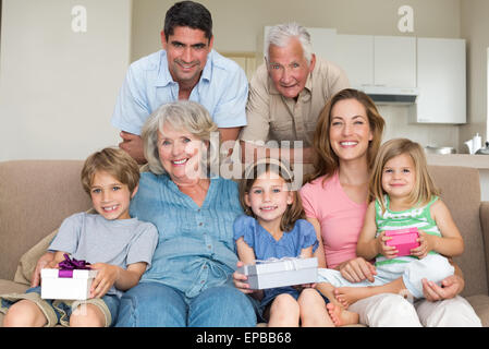 Geschwister halten Geschenke mit Familie im Wohnzimmer Stockfoto