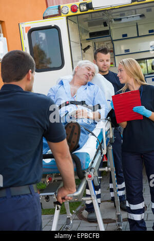 Paramedizinische Team helfen verletzten Mann auf Keilrahmen Stockfoto